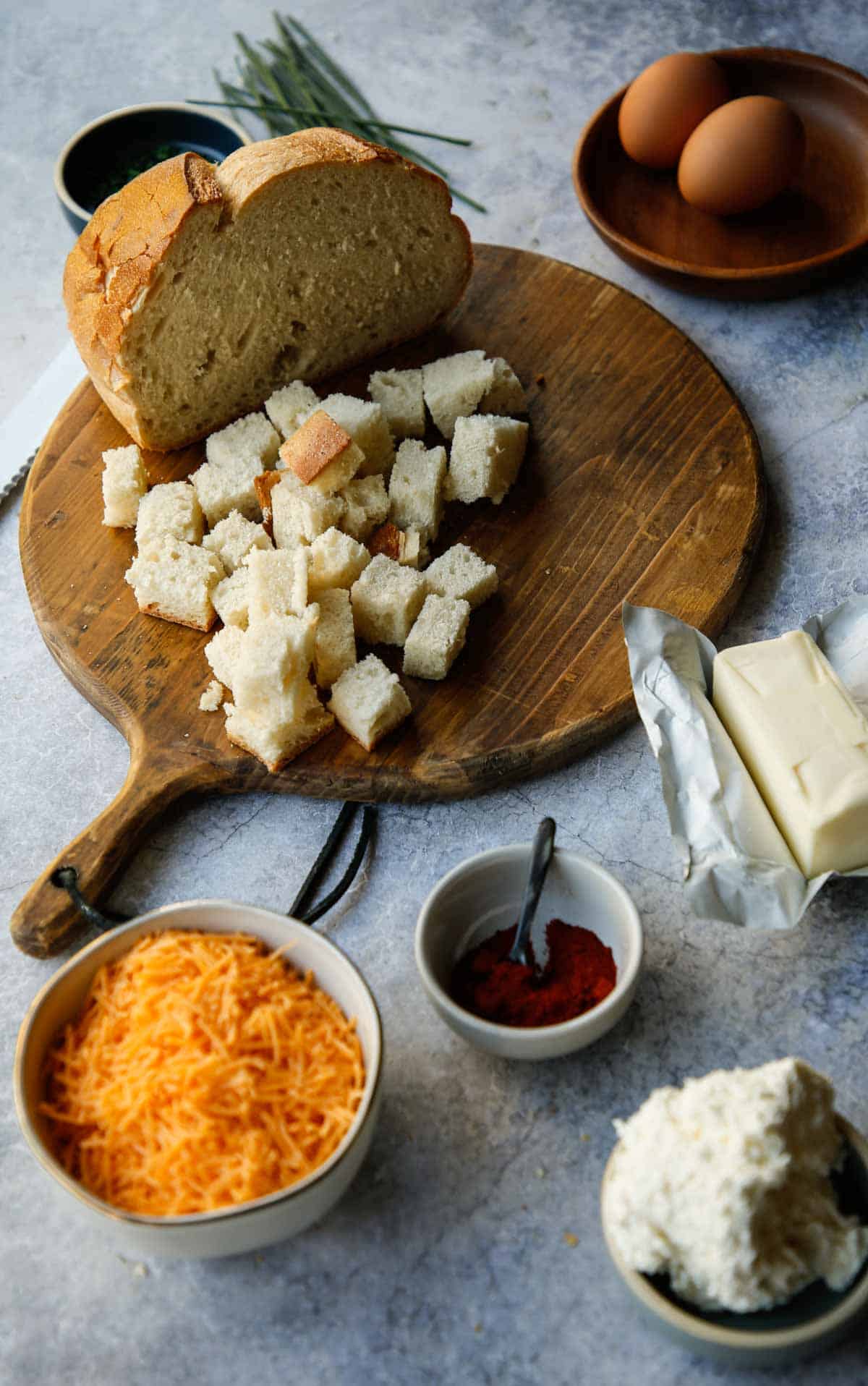 Ingredients laid out on a counter such as bread, cheddar cheese, cream cheese, and eggs