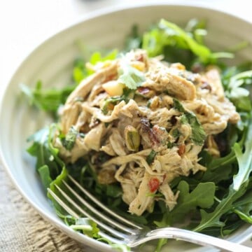 A scoop of chicken salad mixed with yogurt and spices on a bed of greens