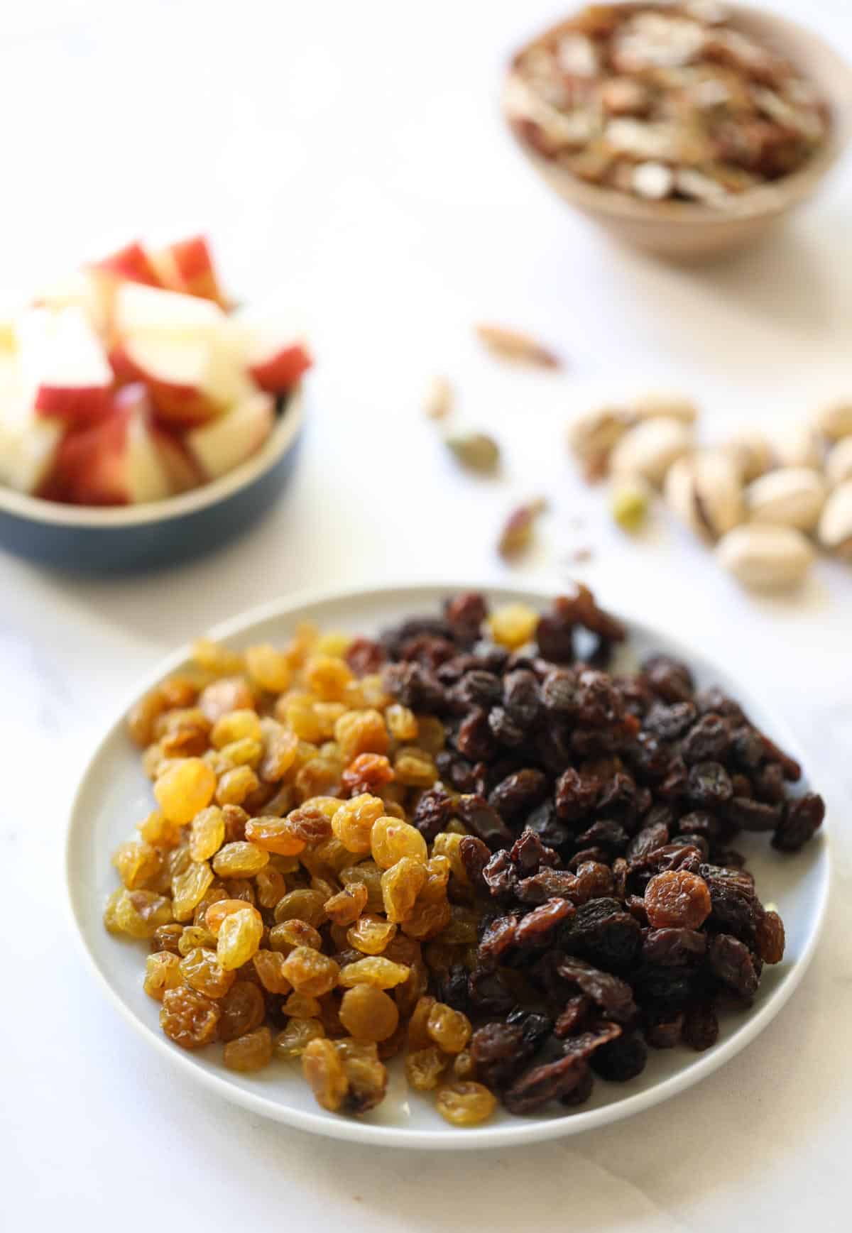 Raisins and apples and nuts laid out on a counter