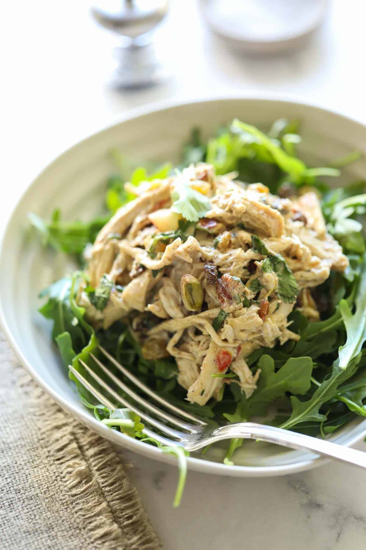 a bowl of greens with a chicken salad on top