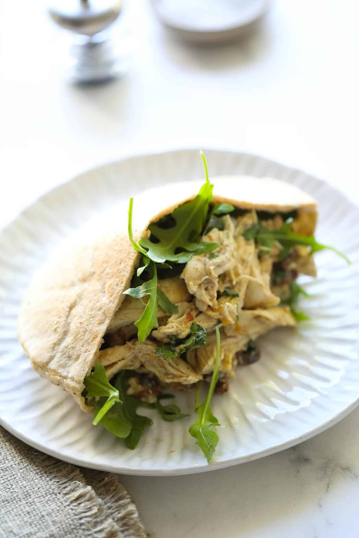 a pita sandwich filled with chicken salad and greens