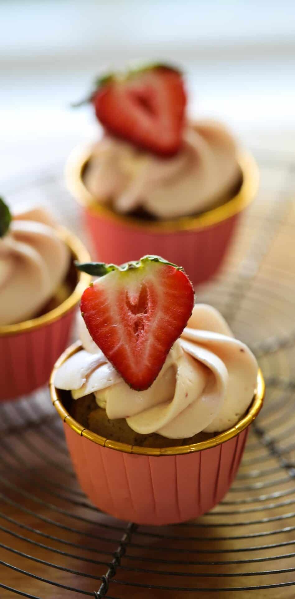 a strawberry cupcake in a pink and gold liner