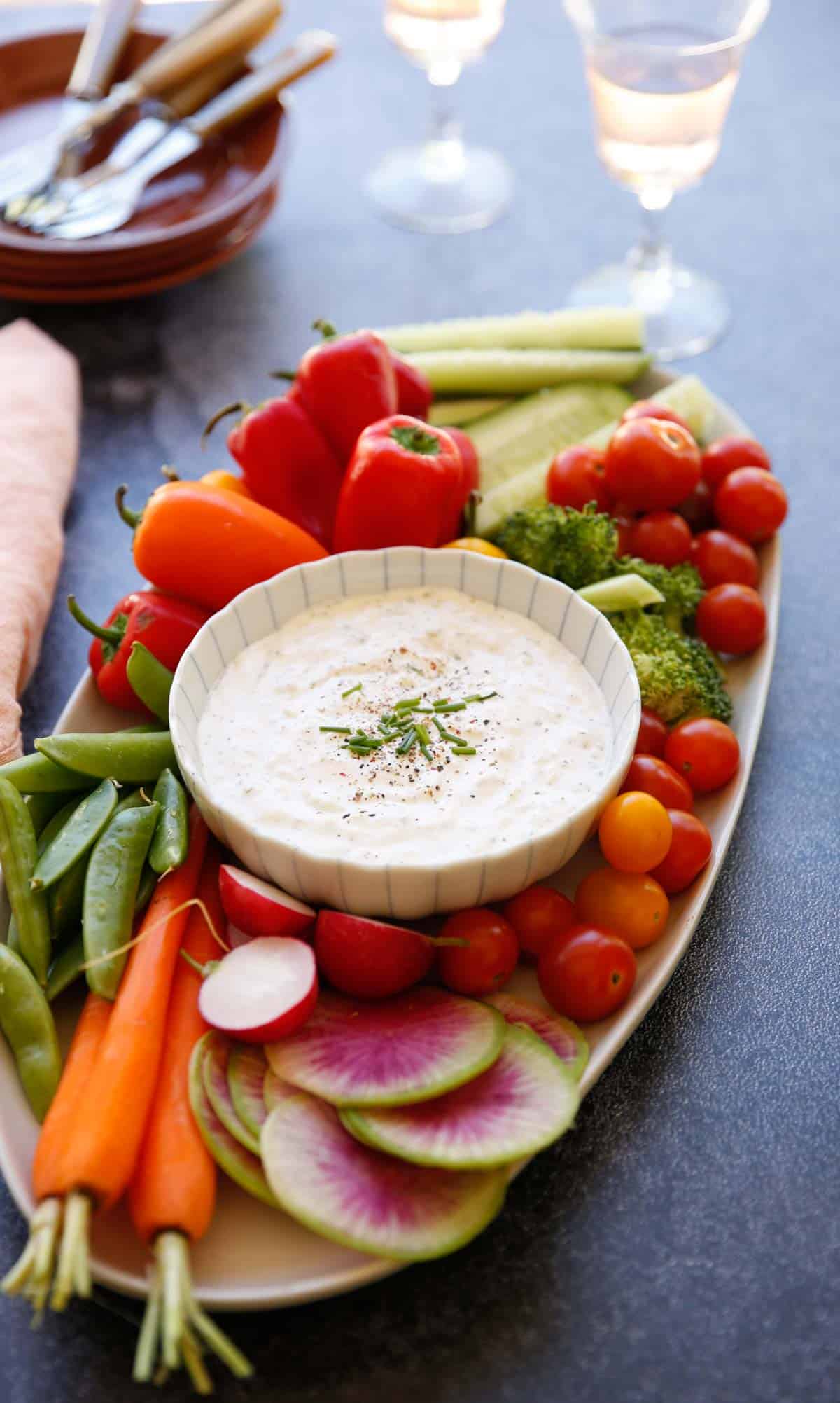 a platter of raw vegeratbles on a platter with dip in a small bowl