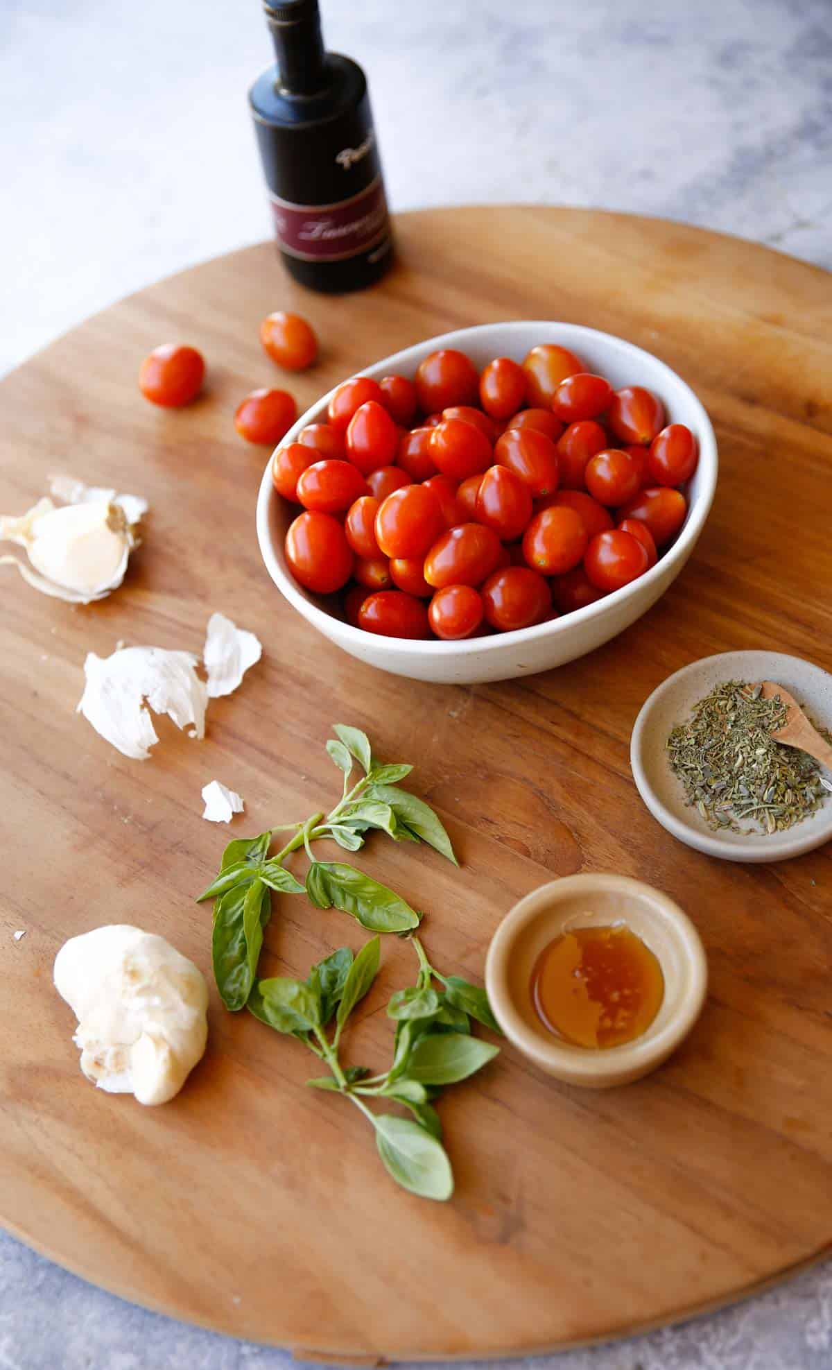 cherry tomatoes, basil, garlic honey and balsamic vinegar laid out on a board