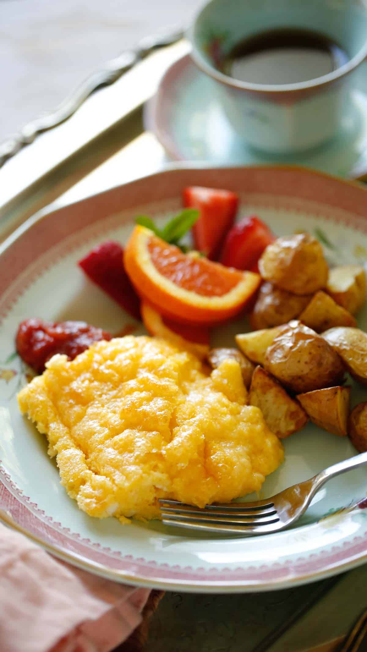 a plate of eggs, potatoes, salsa and fruit