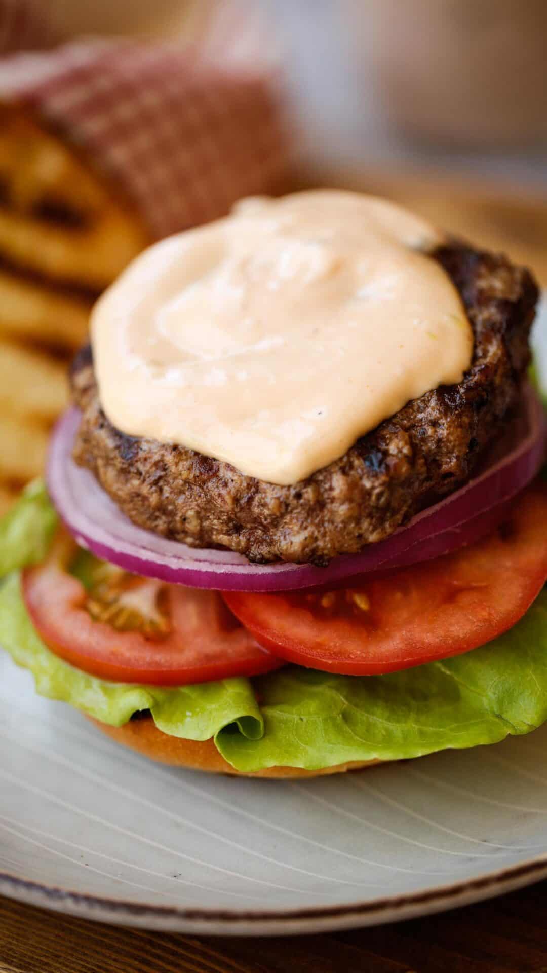 an open faced burger with burger sauce on top and grilled bun to the side