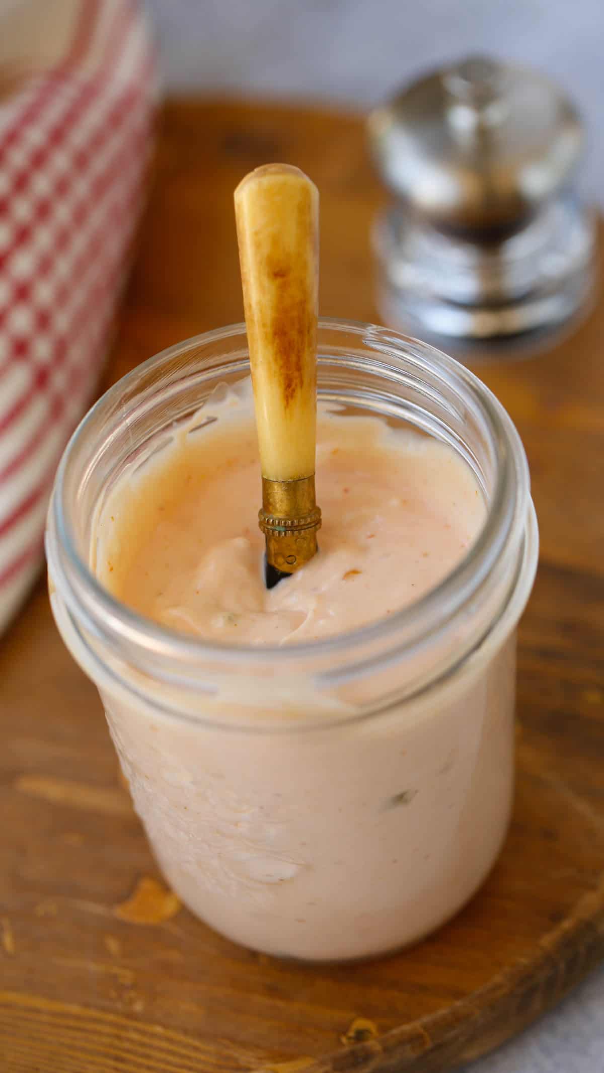 a mason jar filled with sauce and a spreading knife inside