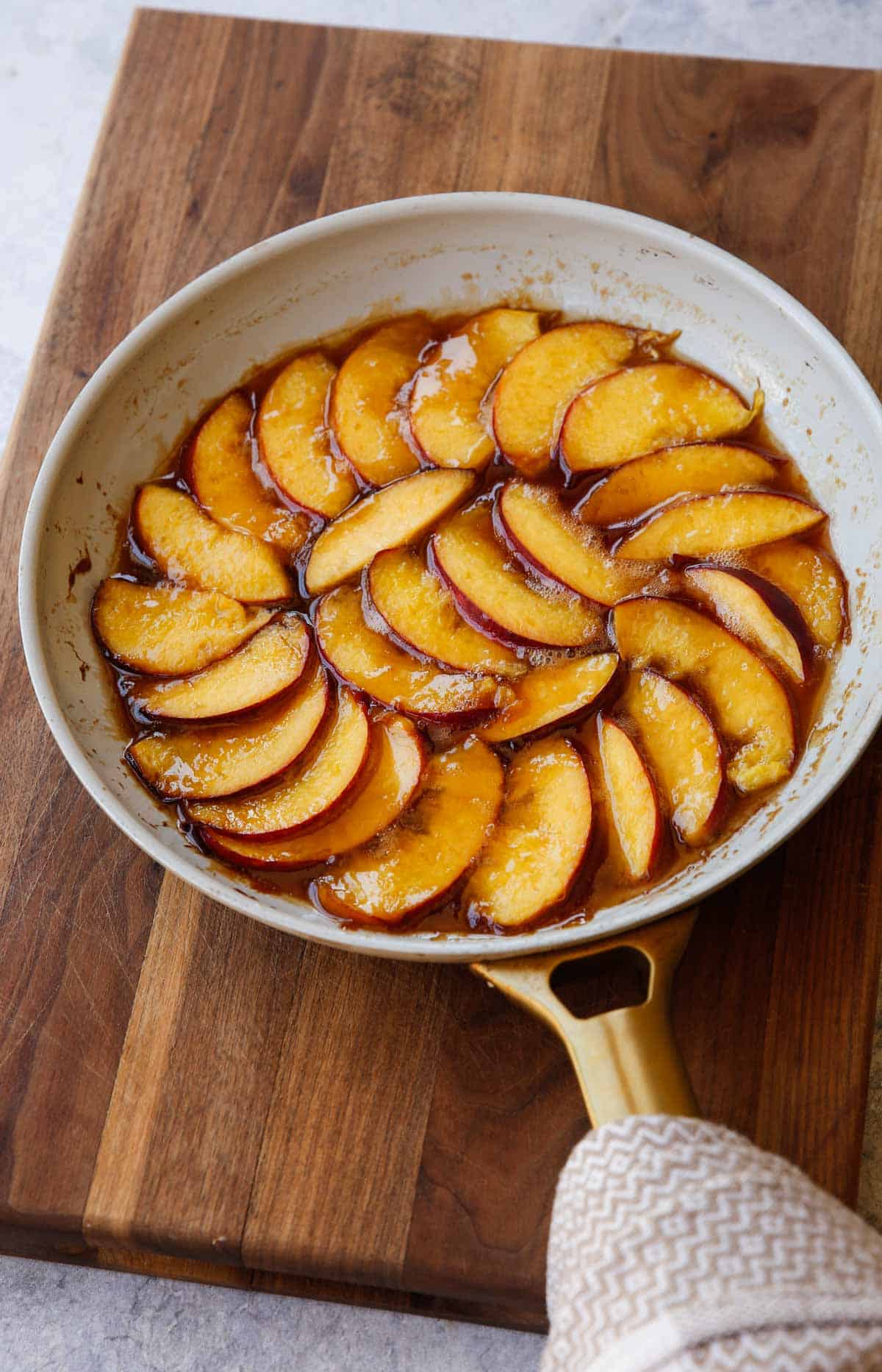 sliced peaches cooking in caramel syrup in a non-stick pan