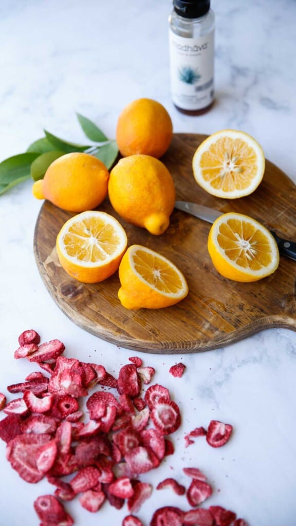 lemon on a cutting board with freeze-dried strawberries and a bottle of agave syrup