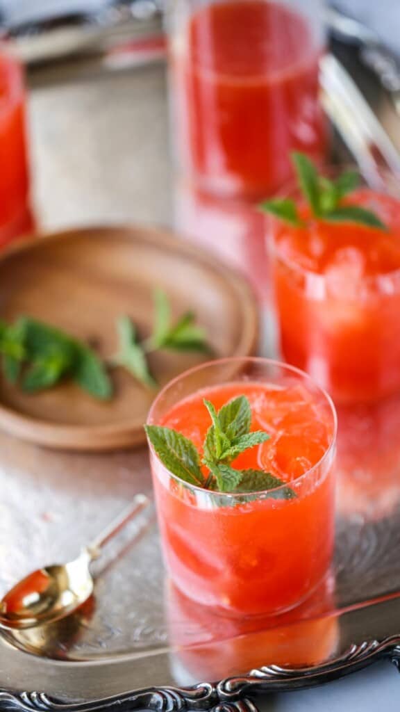 a close up shot of glasses of lemonade with a wood dish holding mint garnish