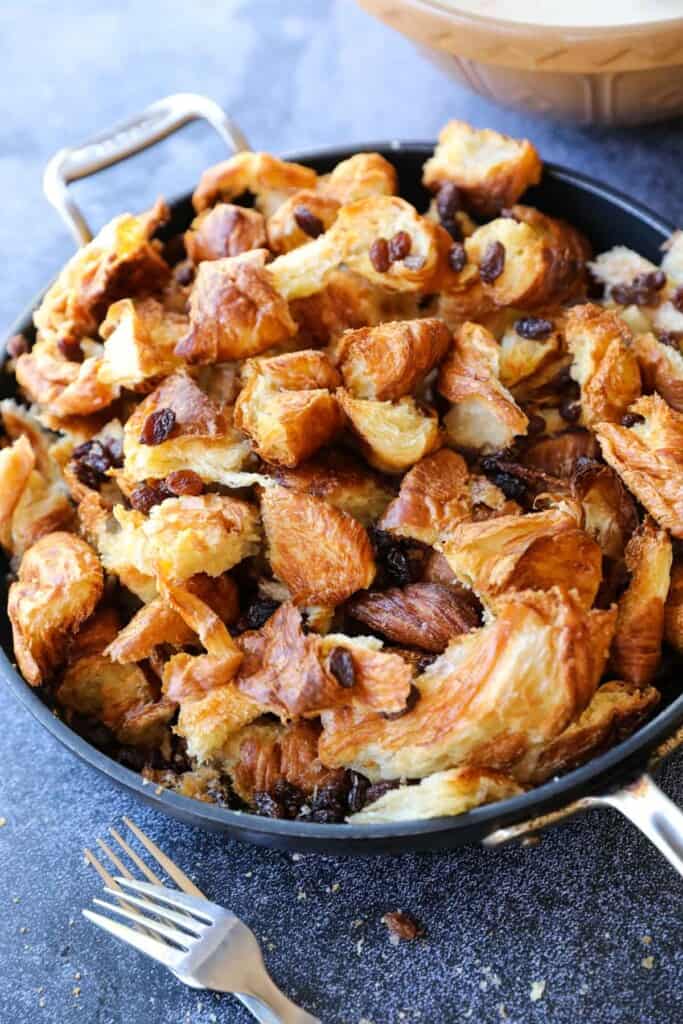 croissants and raisins in a skillet ready to have custard poured over it