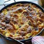 a fully baked bread pudding in a skillet dusted with powdered sugar on a table