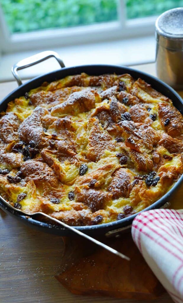 a fully baked bread pudding in a skillet dusted with powdered sugar on a table