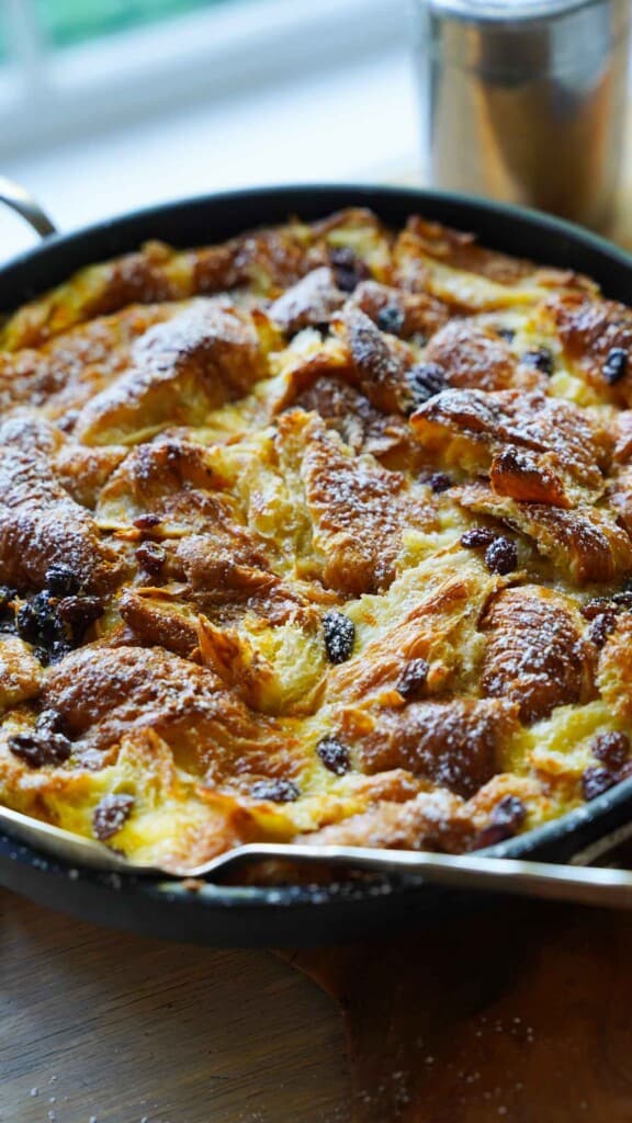 Close up shot of croissant bread pudding with raisins in a skillet