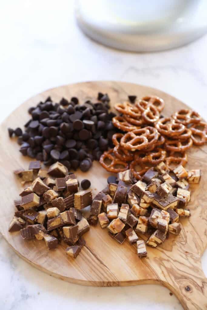 A cutting board with chocolate chips, Chopped Candy and Mini Pretzles
