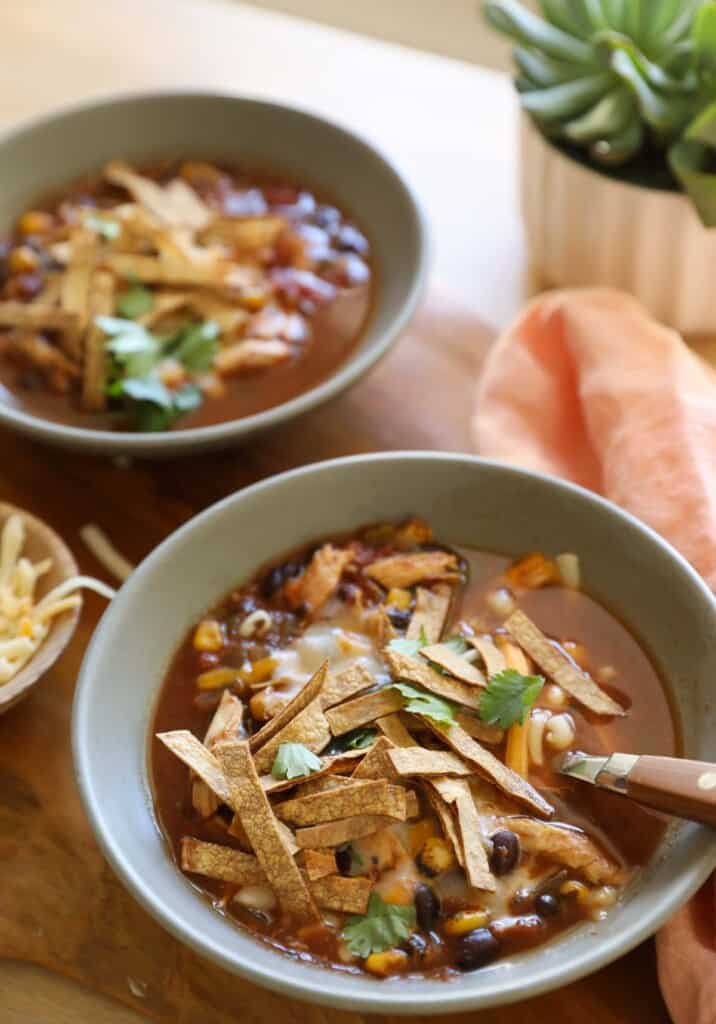 Chicken Tortilla Soup in gray bowls with cheese and tortilla strips