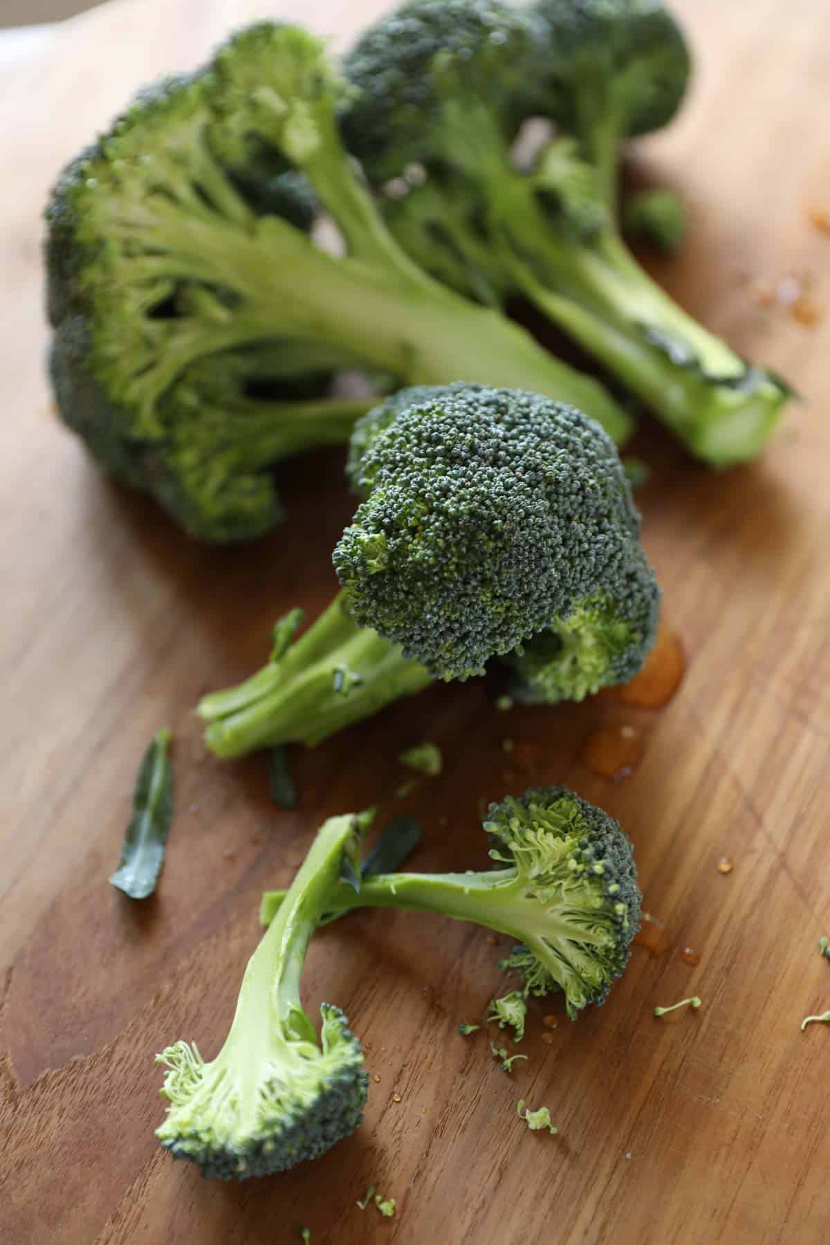 raw broccoli heads on a cutting board