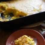 a corn pudding casserole dishj in the background and a serving on a plate
