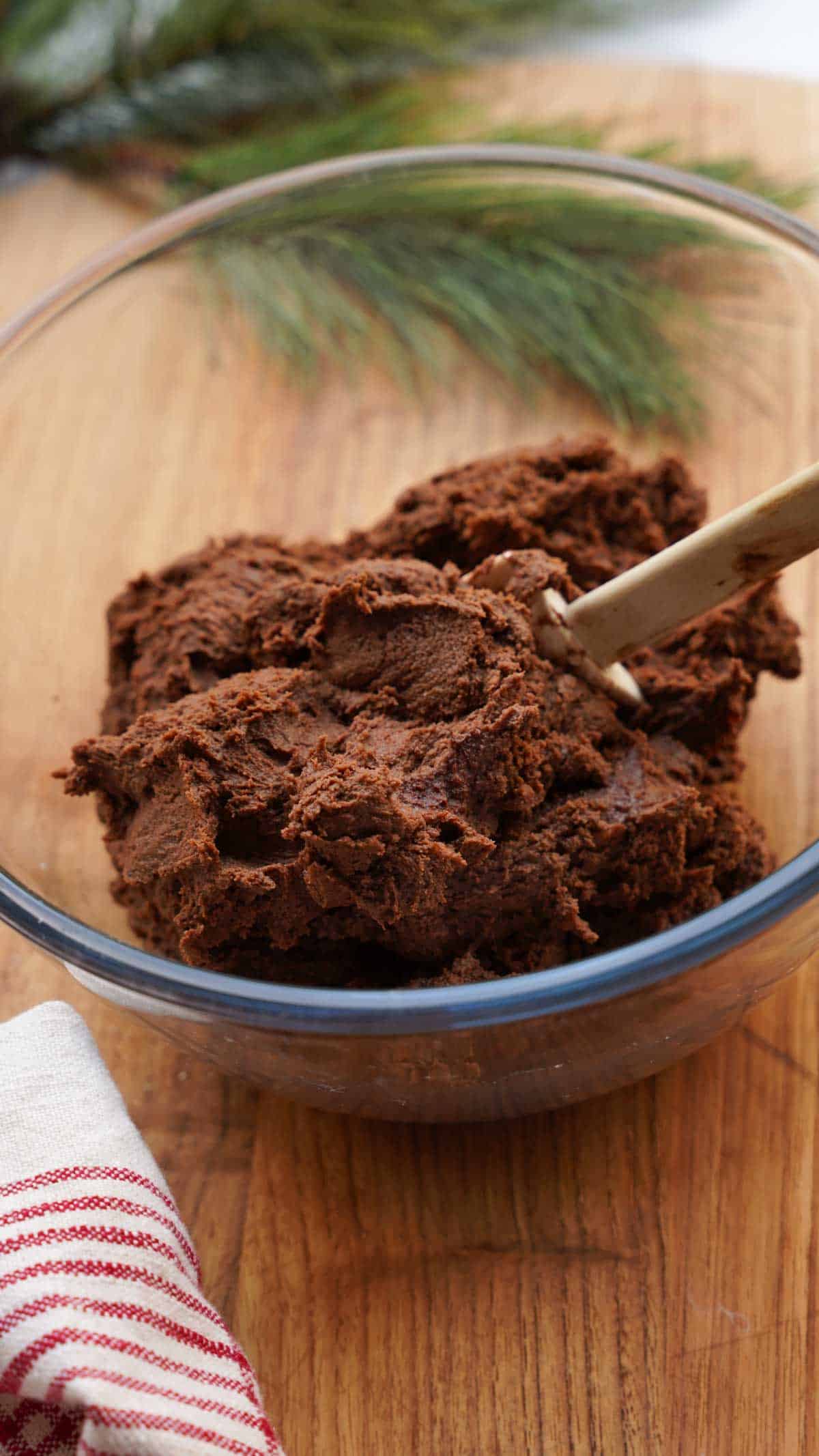 Chocolate cookie dough in a clear bowl with a spatula