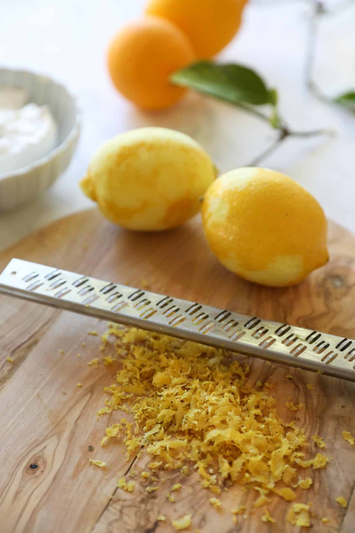 lemons being zested on a cutting board