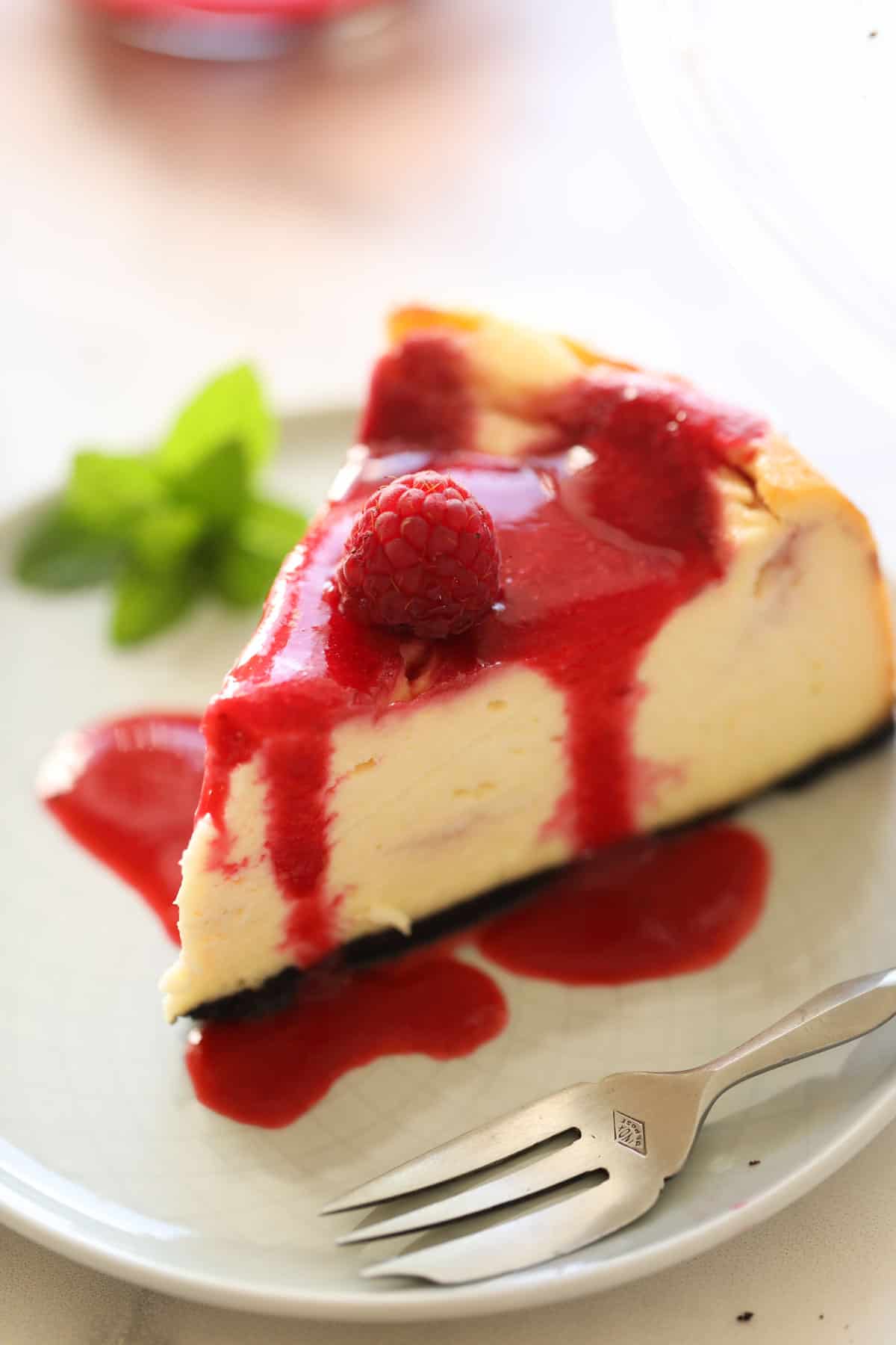 a slice of cheesecake on a plate with raspberry sauce poured over the top