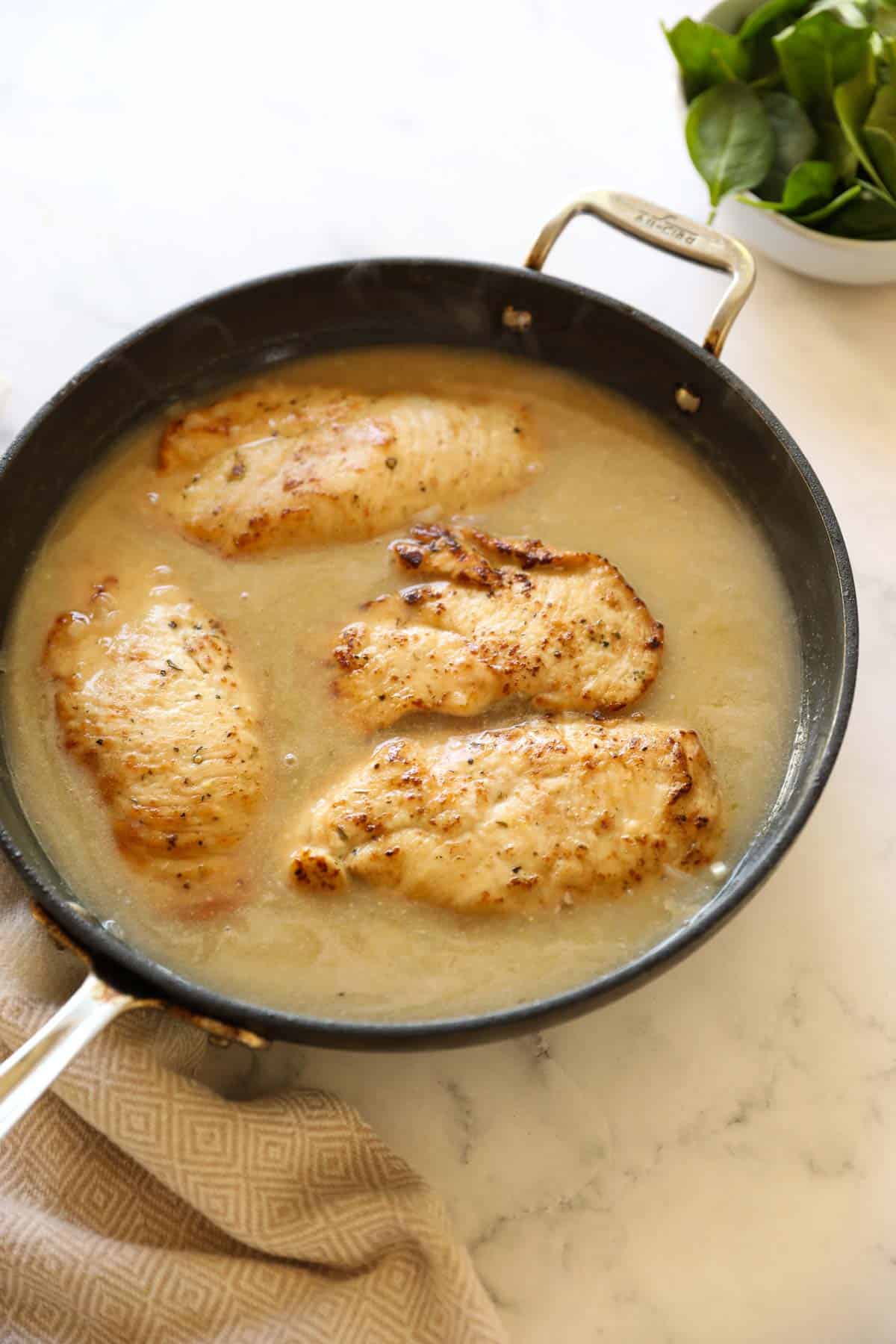 chicken breasts seared in a pan with sauce