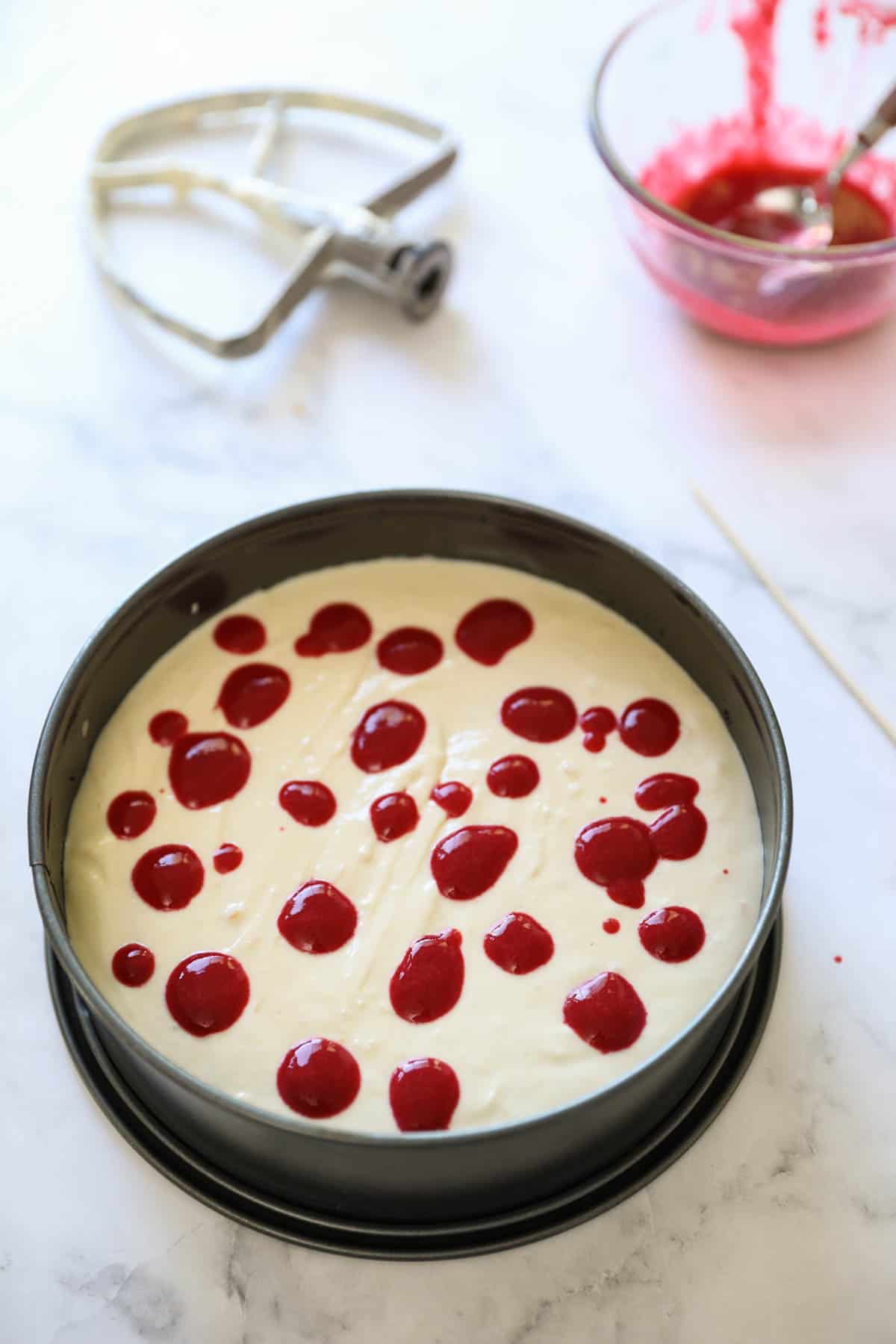 A cheesecake with raspberry puree dots in the center for swirling