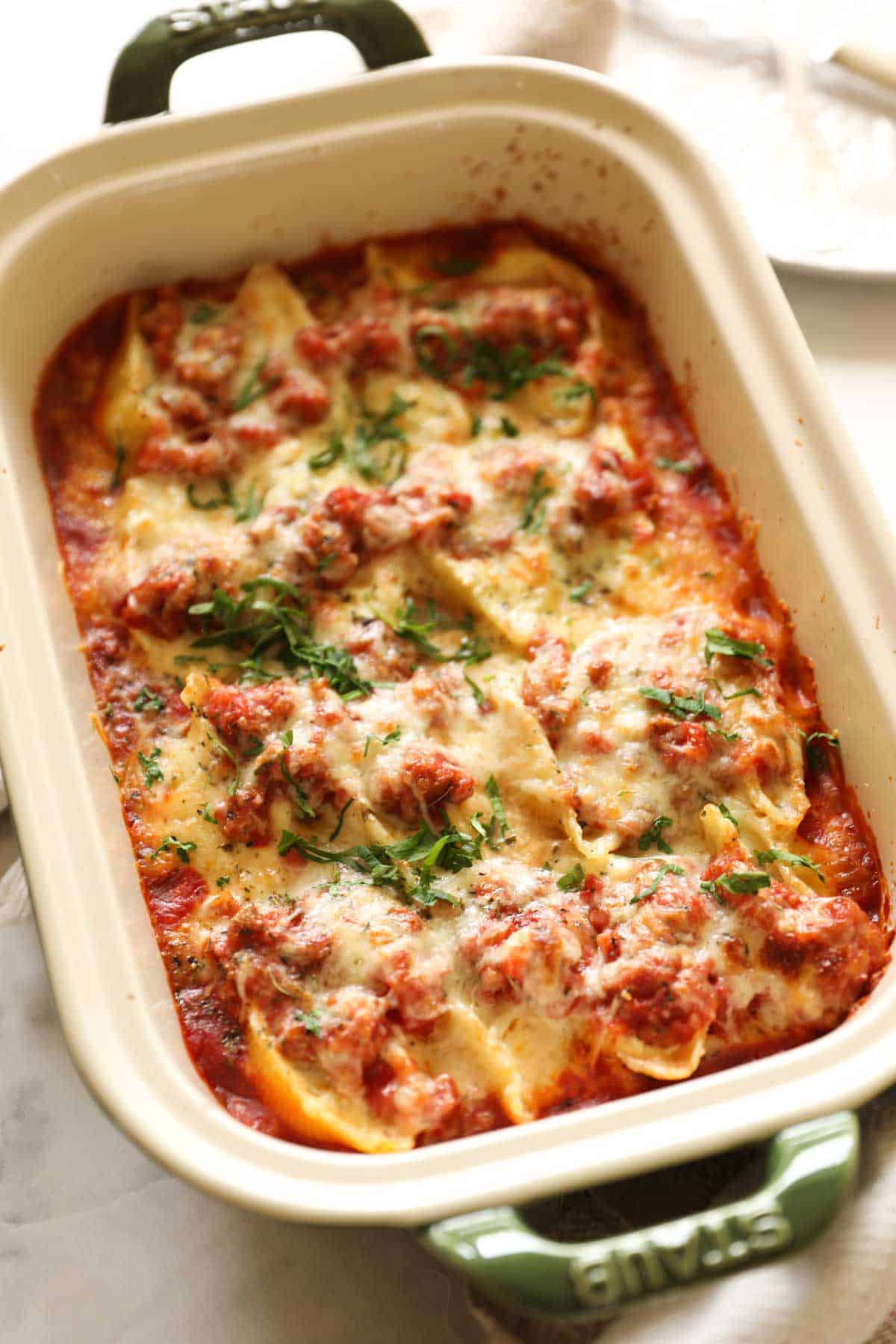 A casserole dish filled with baked stuffed shells covered in mozzarella cheese