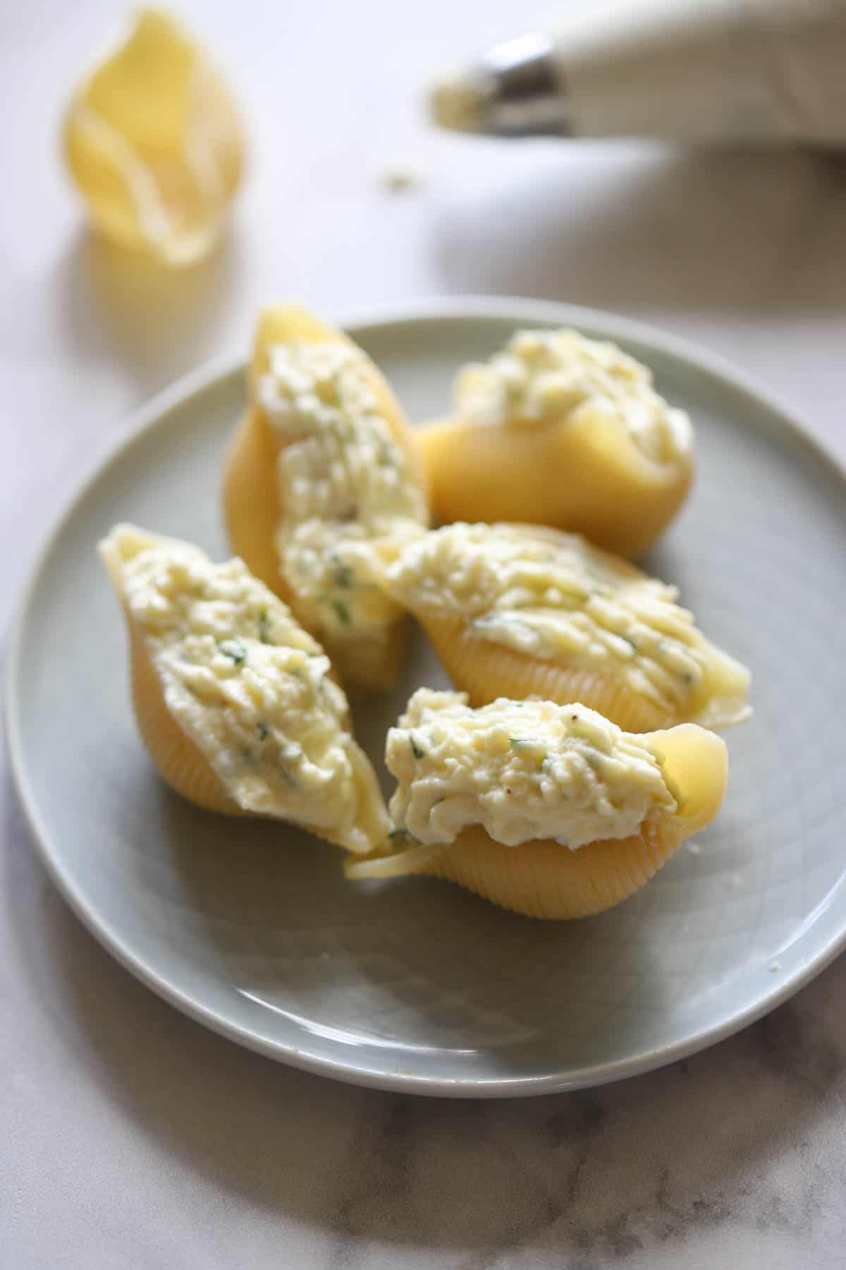Cooked Pasta shells on a plate stuffed with ricotta cheese