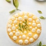 a lemon curd tart decorated with dollops of whipped cream and citrus blossoms