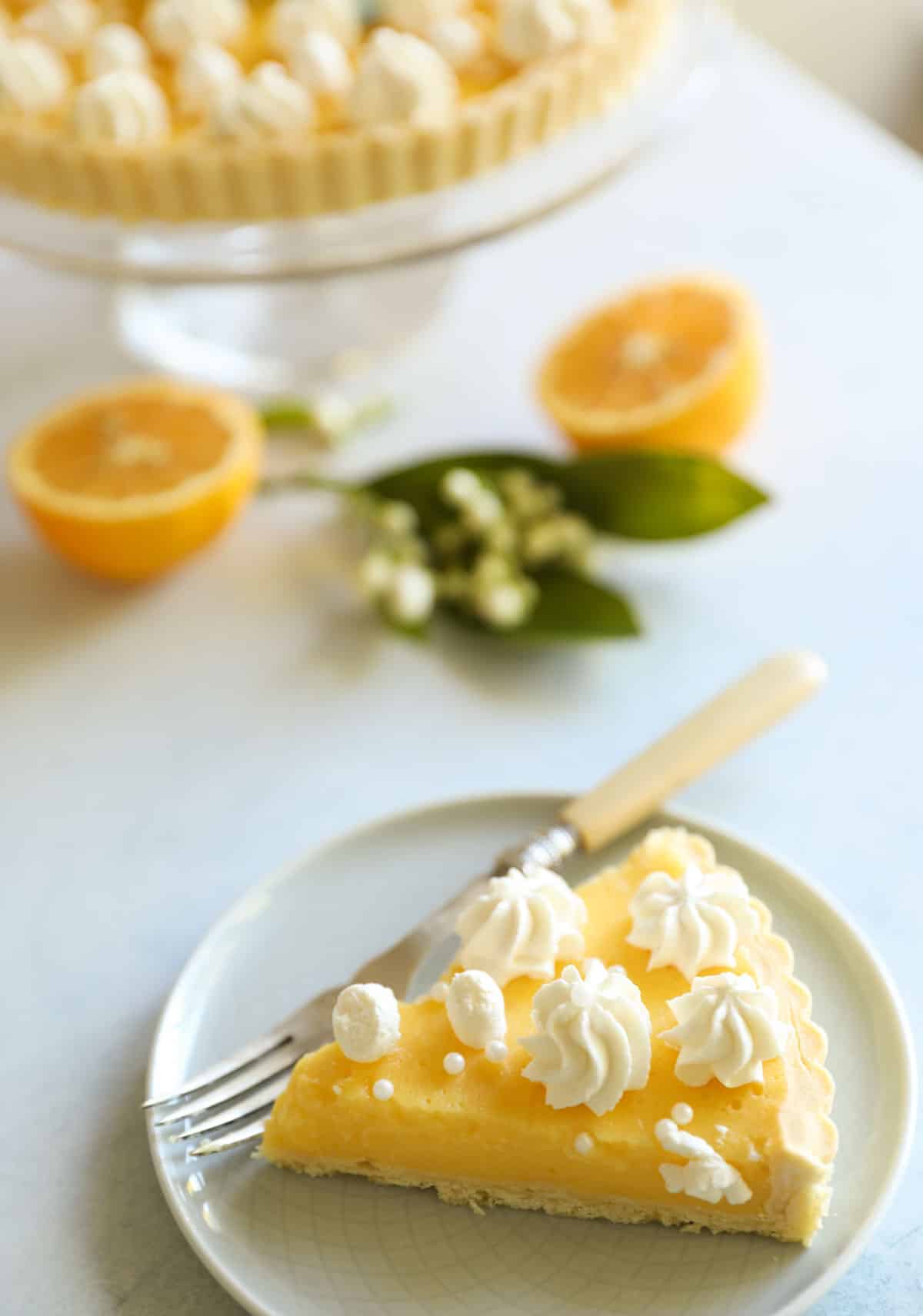 a slice of lemon pie with whipped cream and sliced lemons and citrus blossoms