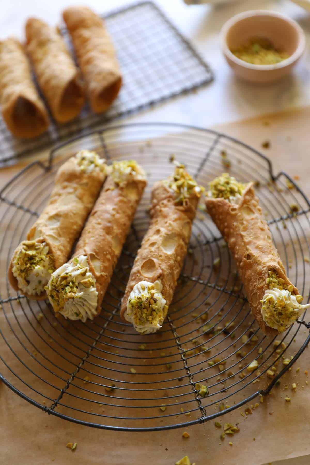 a wire rack with cannoli shells being filled