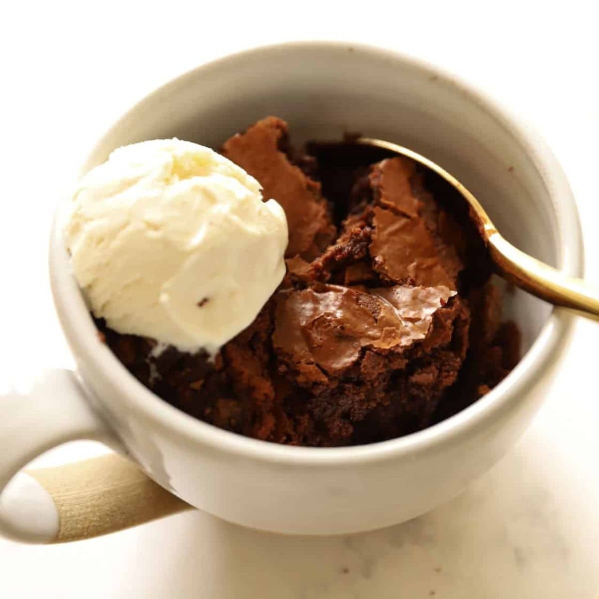 Brownie cake scooped into a mug with ice cream