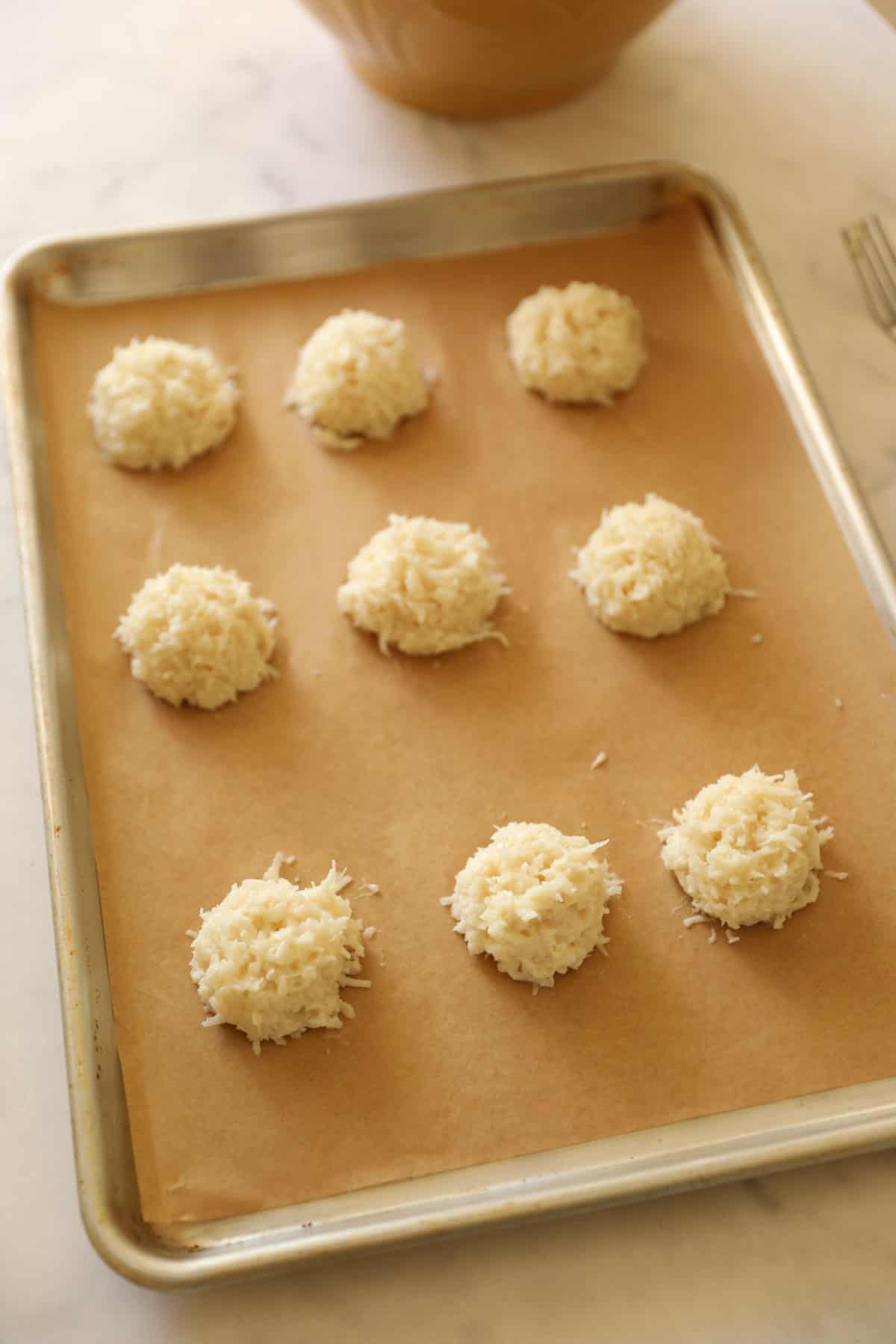 cookie batter balls laid out on a sheet pan lined with parchment paper