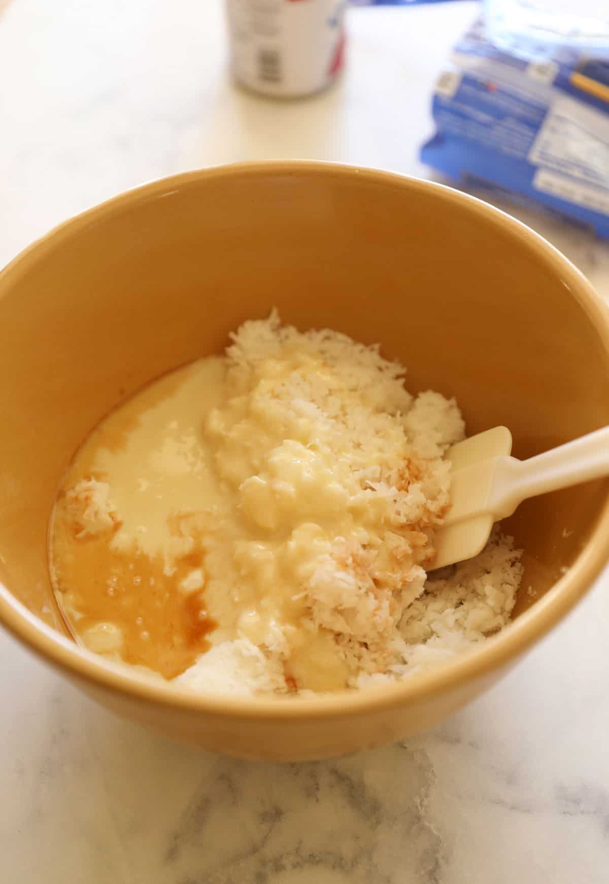 a bowl of sweetened condensed milk, coconut, vanilla and salt