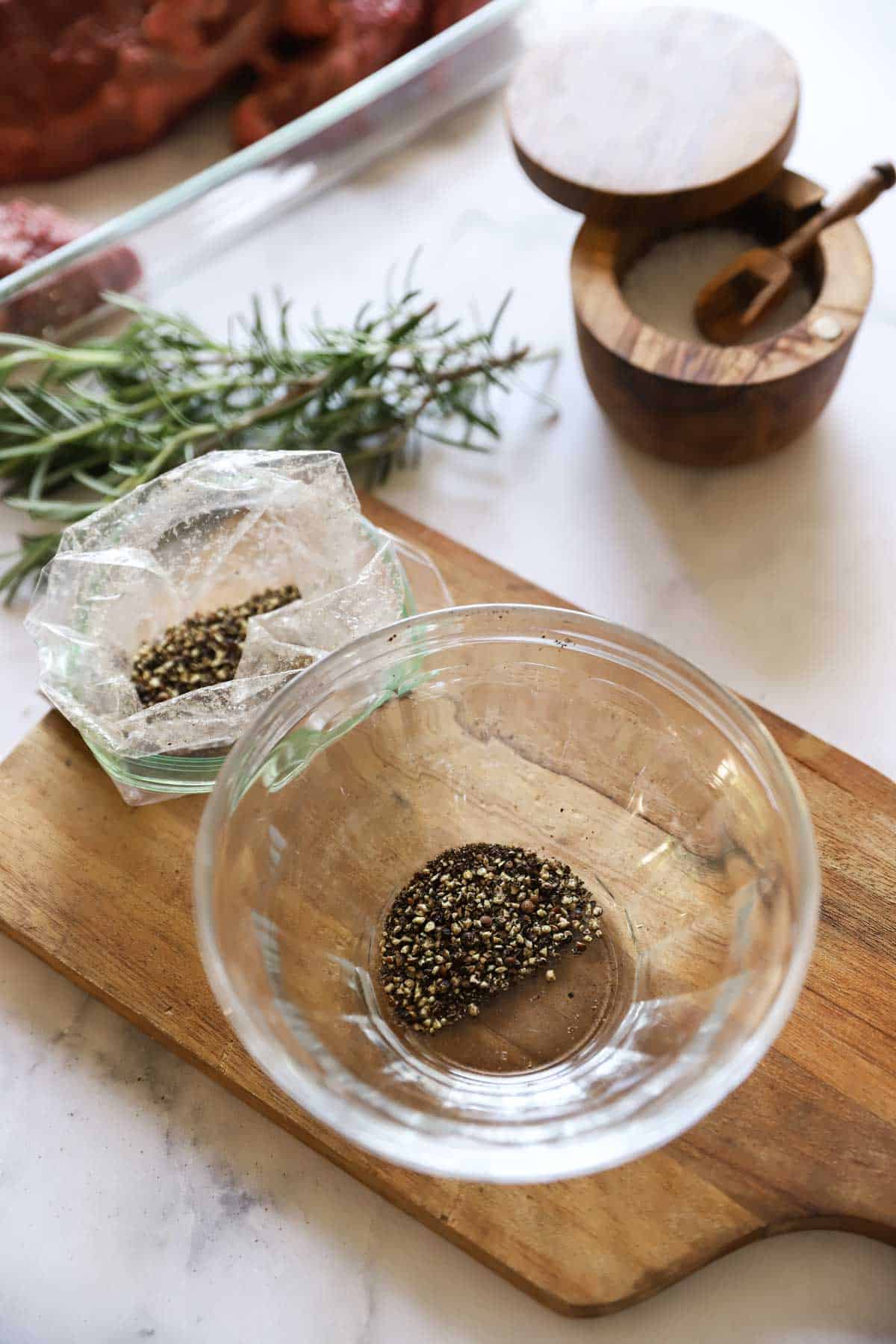 a bowl of cracked pepper and rosemary sprigs