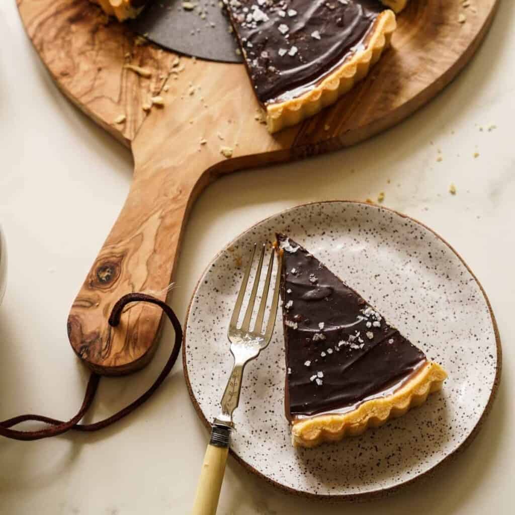 a slice of salted chocolate caramel tart on a plate