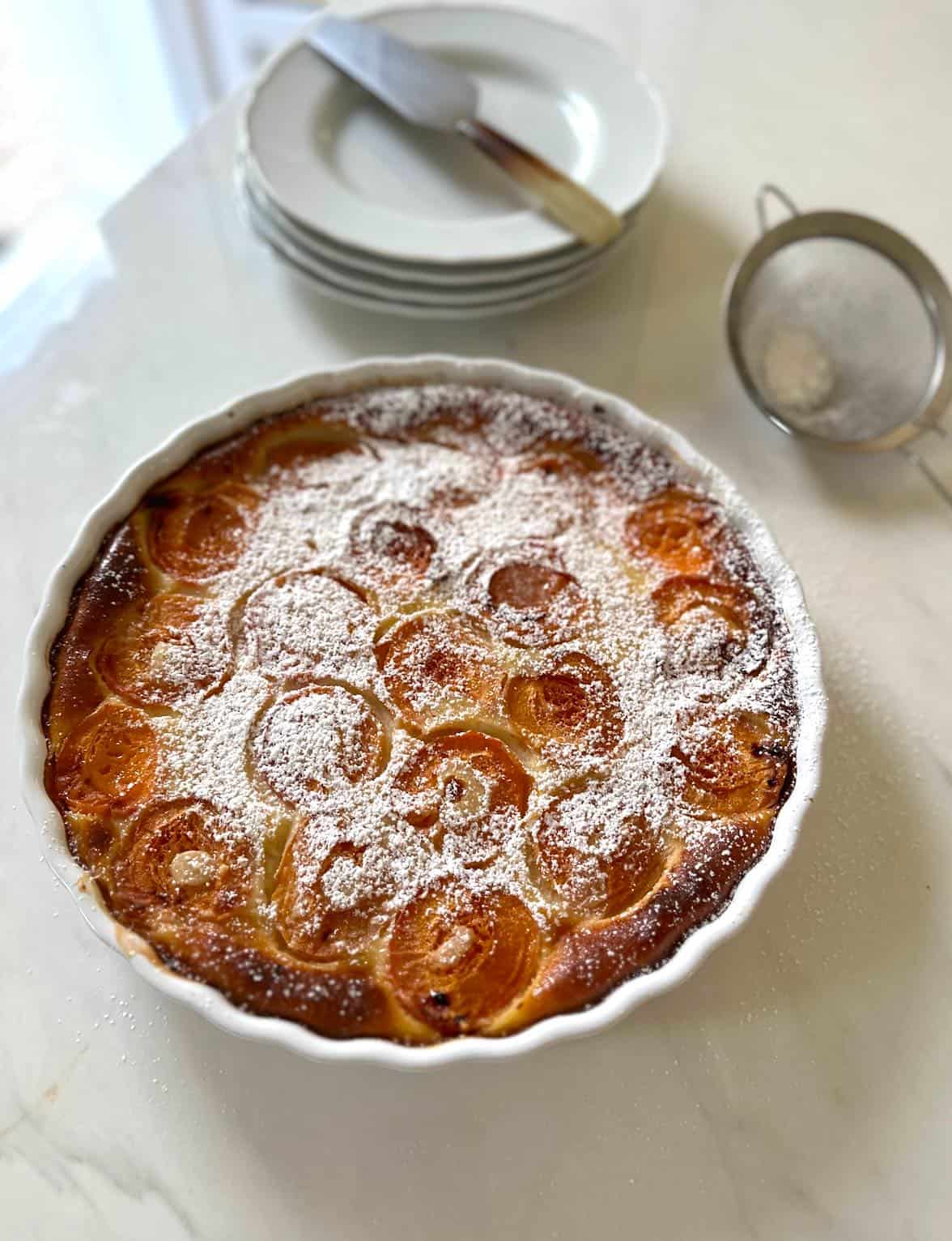 Apricot Clafoutis baked in a white quiche dish with powdered sugar