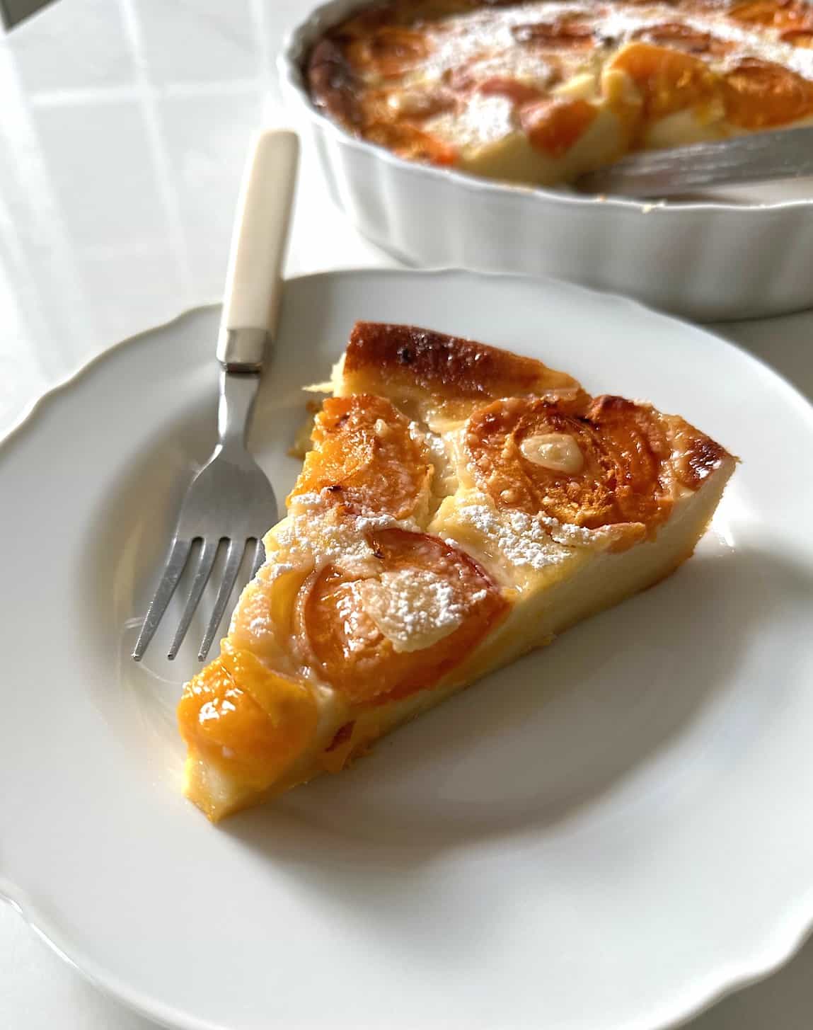 A slice of clafoutis with apricots on a plate