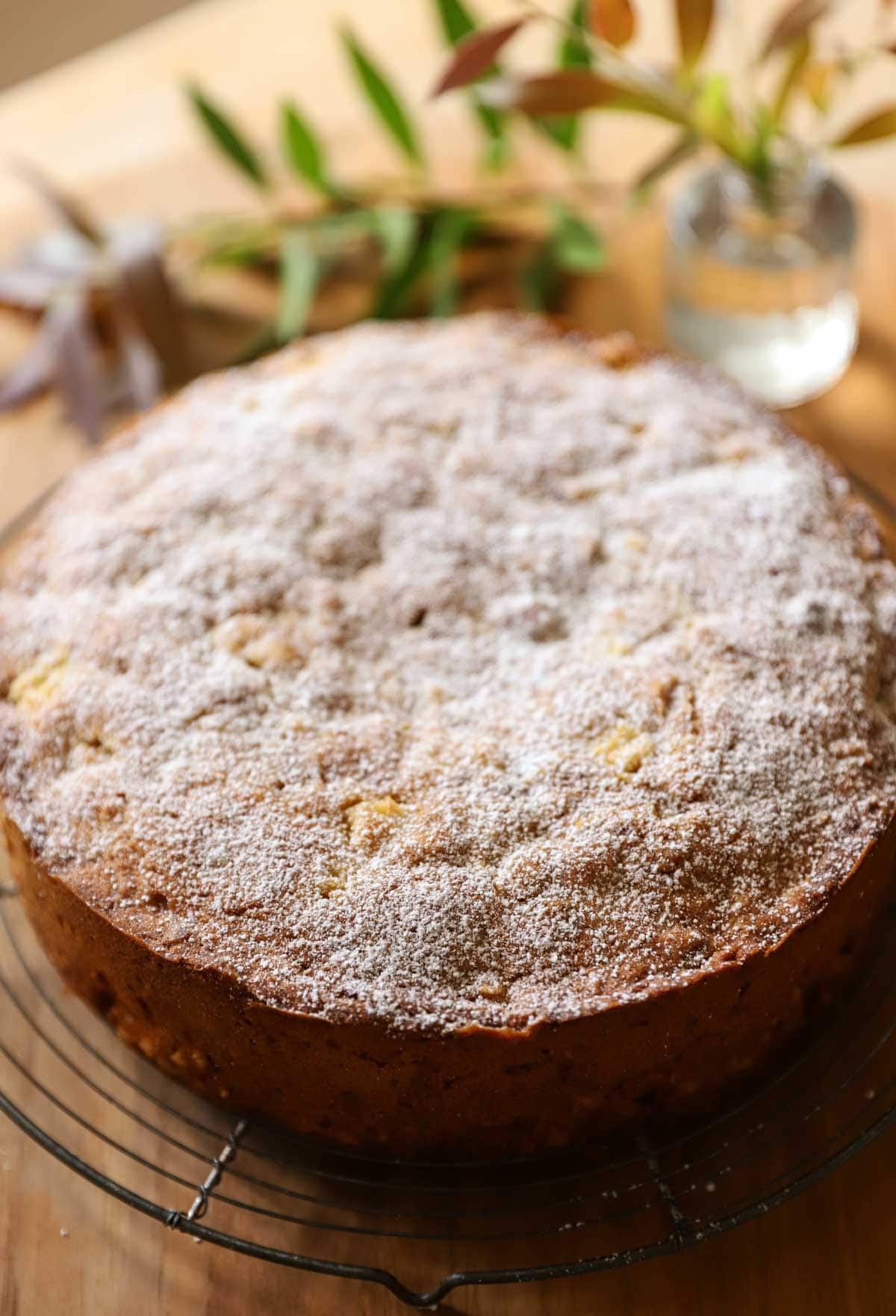 A fully baked cake on a cooling rack with a dusting of powdered sugar.