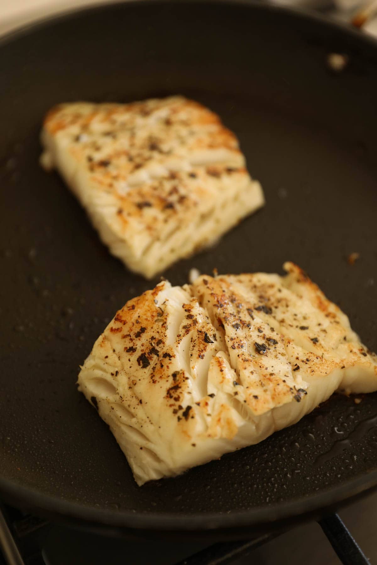 flakey cod fish seared in a non-stick pan