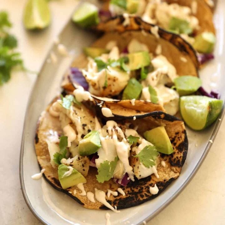 Fish tacos on a platter with garnishes