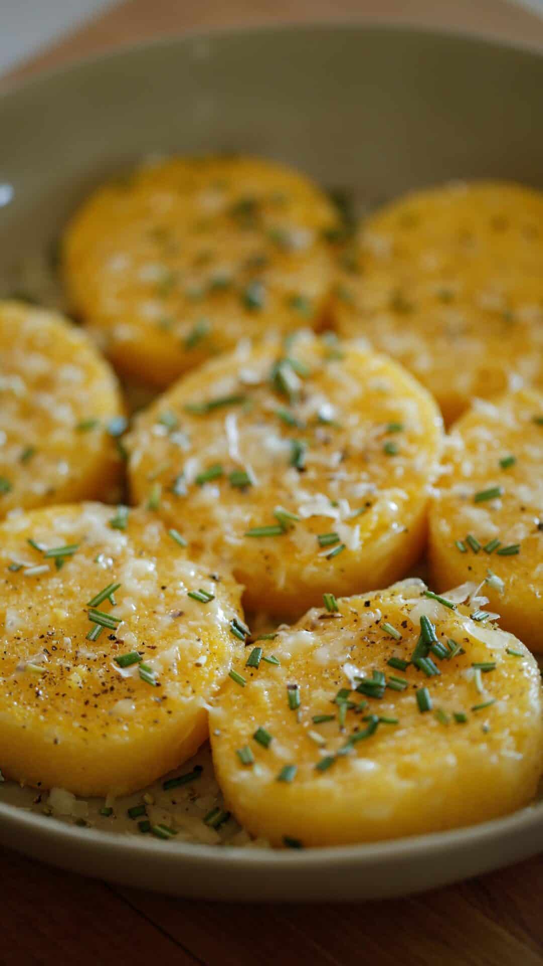 polenta cakes in a bowl with fresh rosemary and parmesan cheese