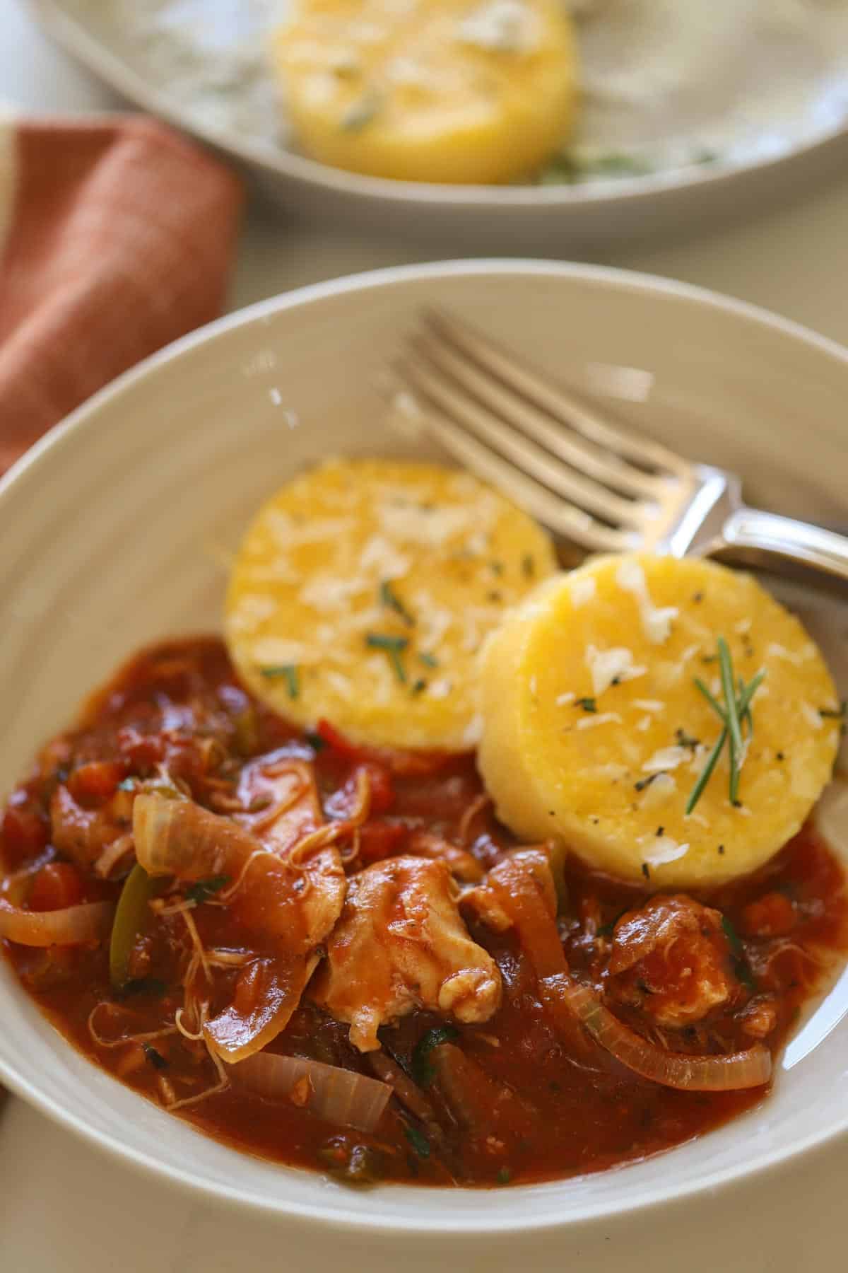 a bowl of slow cooker chicken cacciatore with polenta cakes