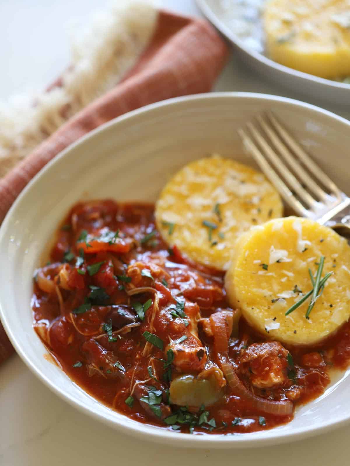 Chicken cacciatore with polenta cakes in a bowl