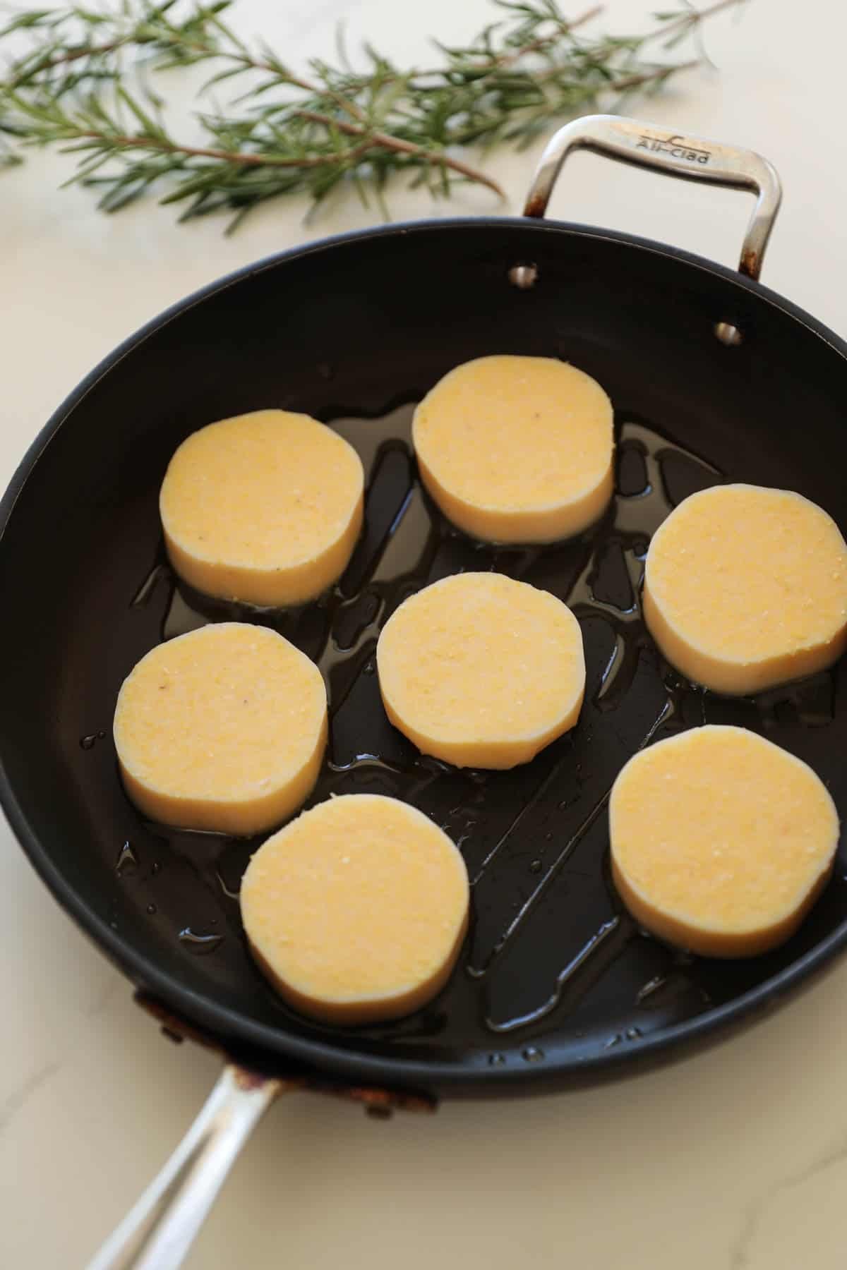 sliced polenta cakes in a saute pan with olive oil