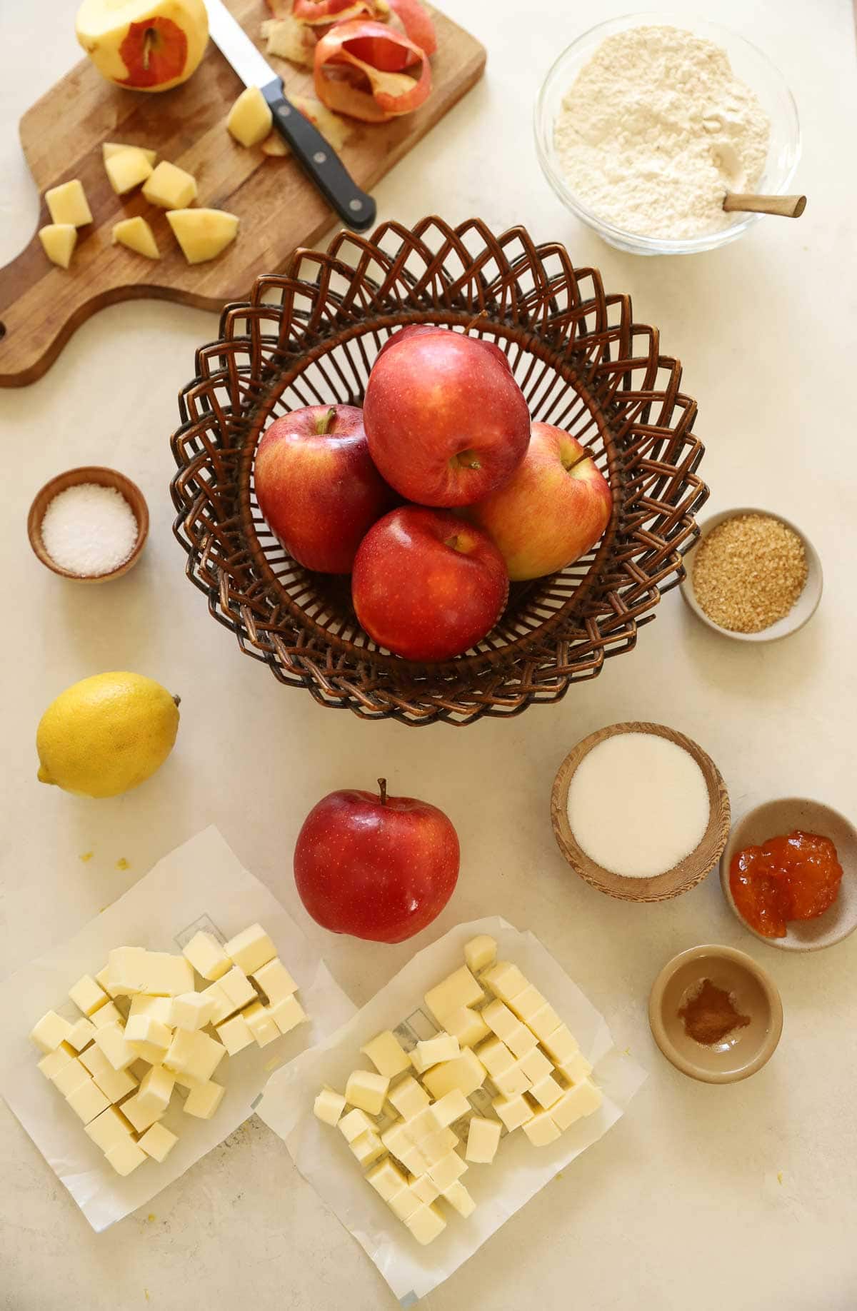 apples, butterm sugar, and other ingredients for pie making on a counter.