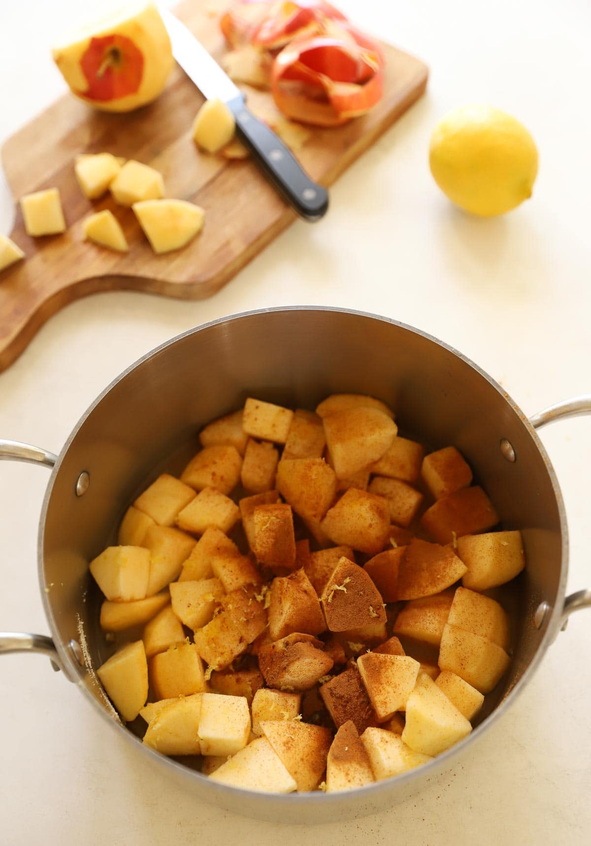 Cubed apples in a pot with cinnamon and sugars.
