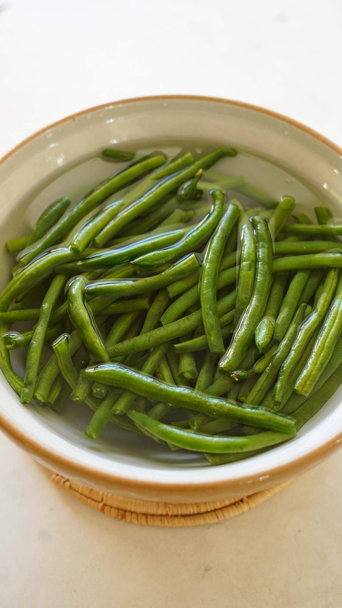 Green beans in a bowl of water cooling