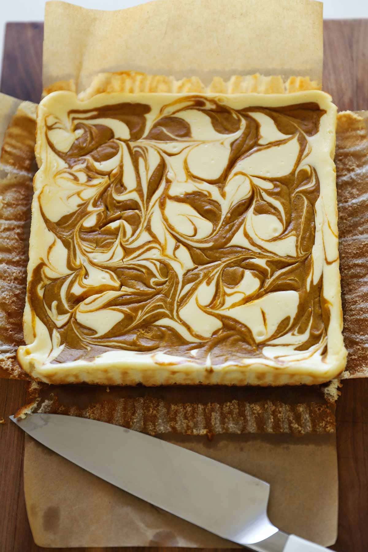 Pumpkin Cheesecake Bars with a swirl about to be sliced